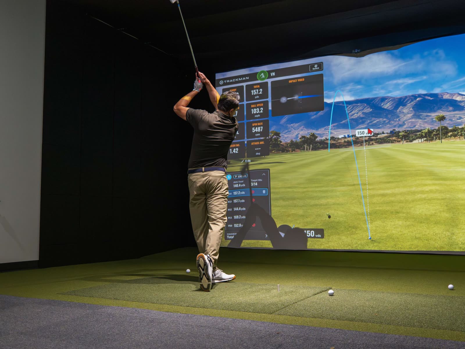 TrackMan golf simulator lesson — a shot traced across the big screen with ball-flight data on every swing